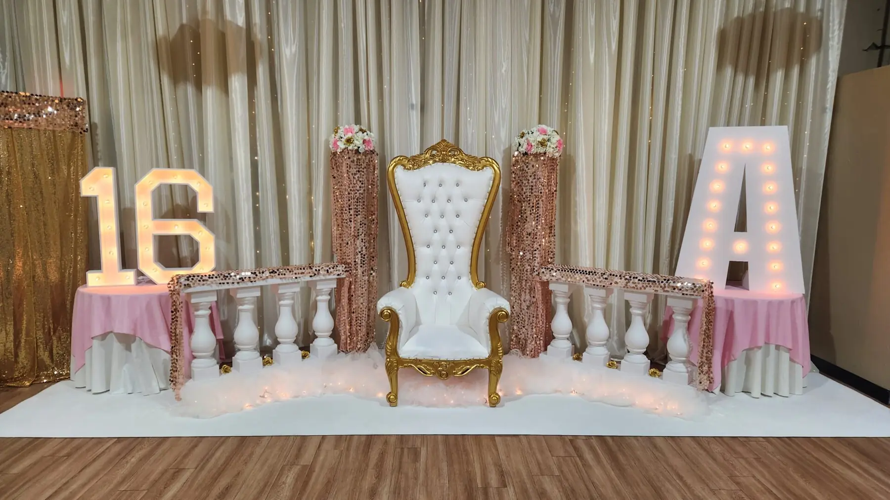A sweet sixteen stage with a white and gold throne and marquee letters