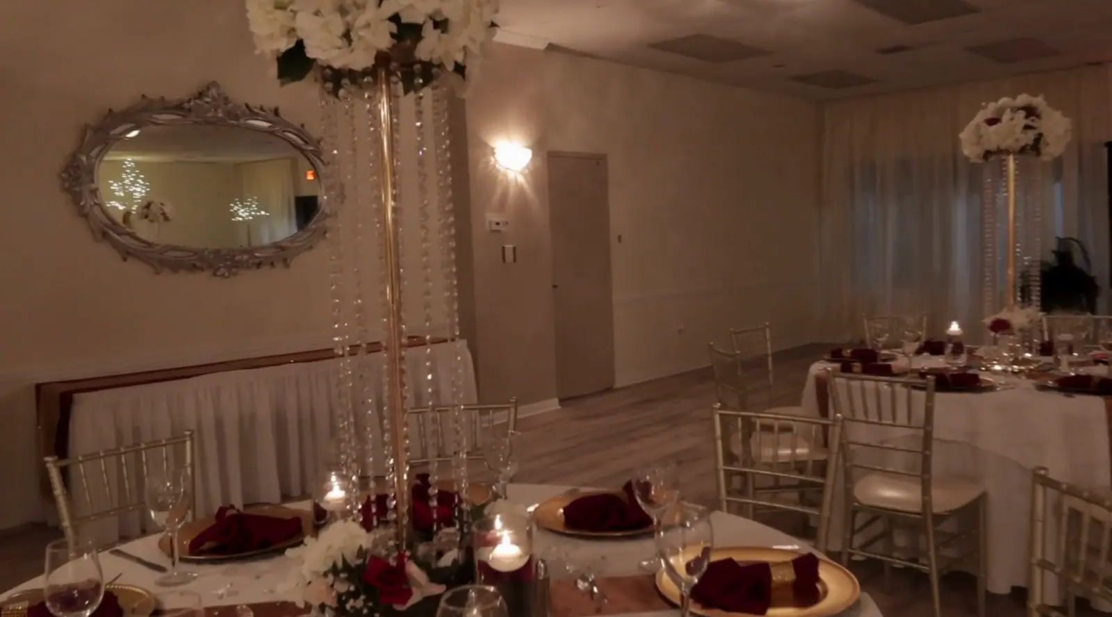 Burgundy napkins, gold chargers and crystal centerpieces by candlelight