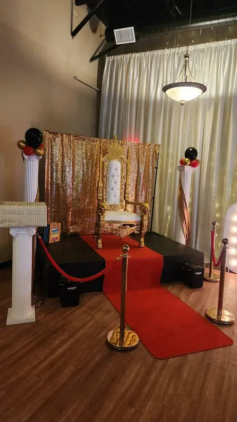 A red carpet with stanchions leading to a stage and throne chair in Studio 78