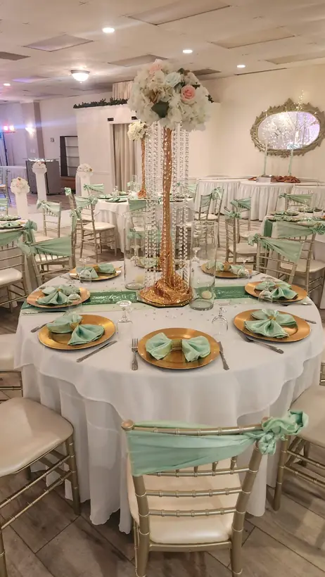 Sage napkins and gold chargers beneath a tall blush floral centerpiece