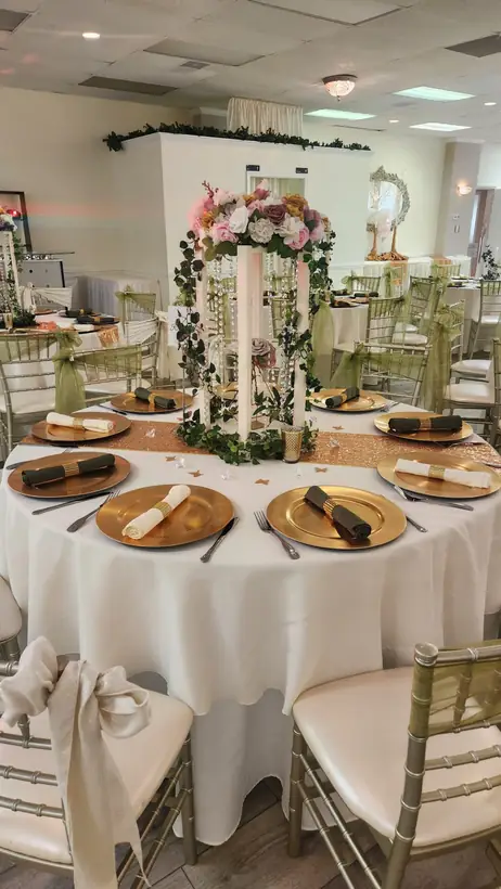 A floral arch centerpiece over gold chargers and ivory linens