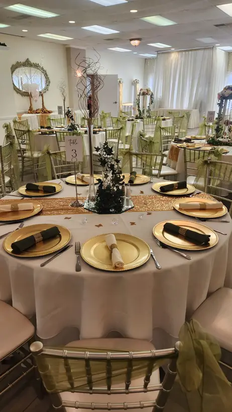 Gold chargers and black napkins on ivory linens, with an ornate mirror behind