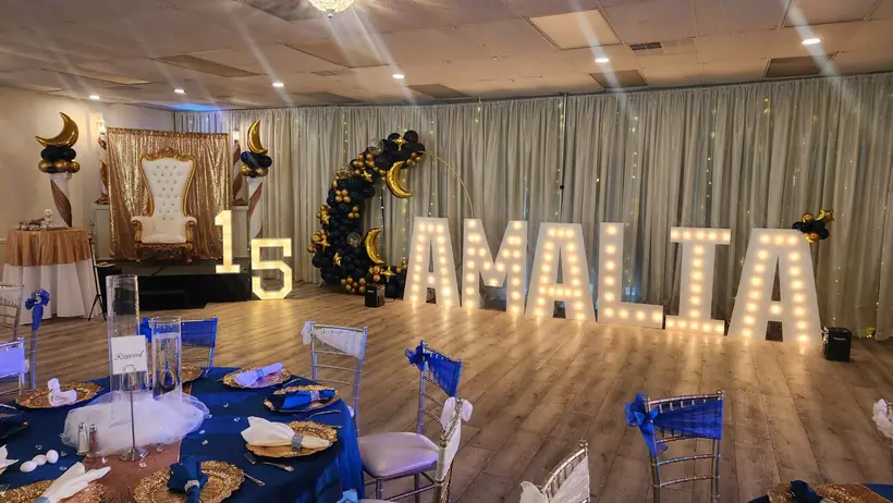 Marquee letters and a crescent moon balloon arch beside the quinceañera throne