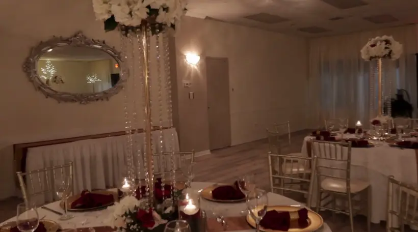 Burgundy napkins, gold chargers and crystal centerpieces by candlelight