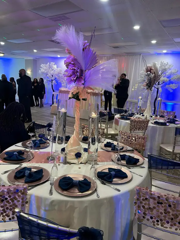 A lavender feather centerpiece over navy and rose gold place settings