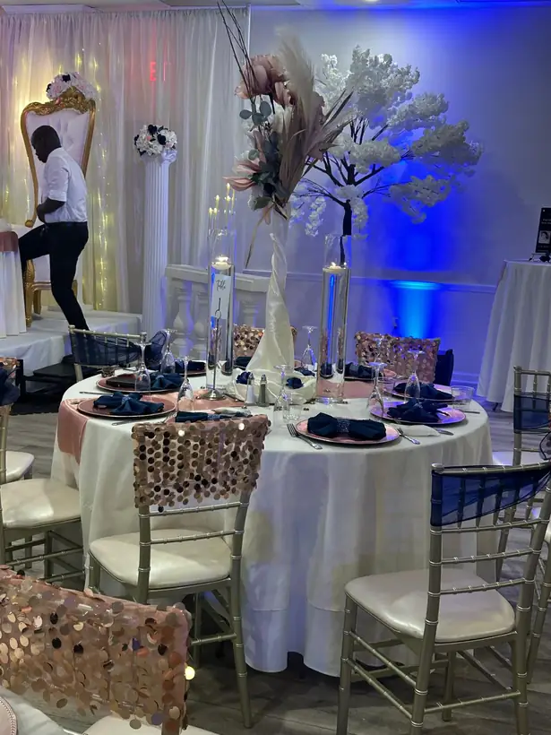 Silver and rose gold place settings with sequin chair covers under blue light
