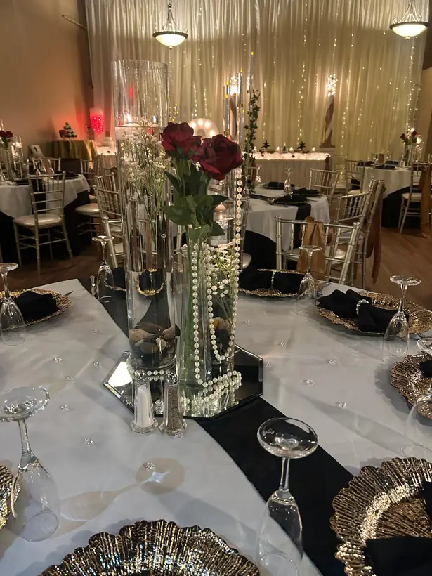 A tall rose and pearl centerpiece over black and white place settings