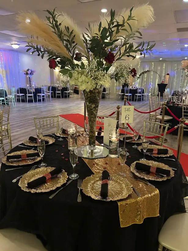 Black linens, gold sequin runners and gold chargers under a pampas and rose centerpiece