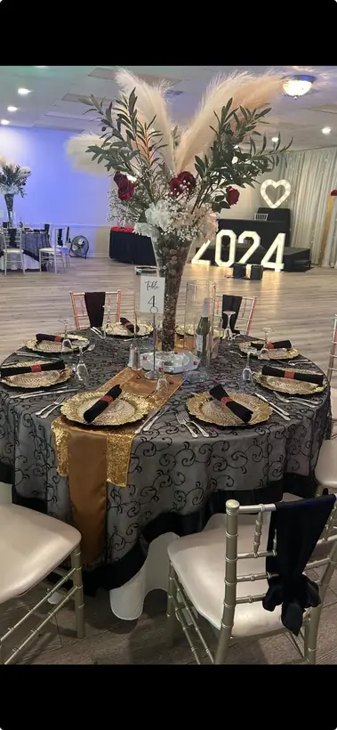 A pampas and rose centerpiece over black, silver and gold tables