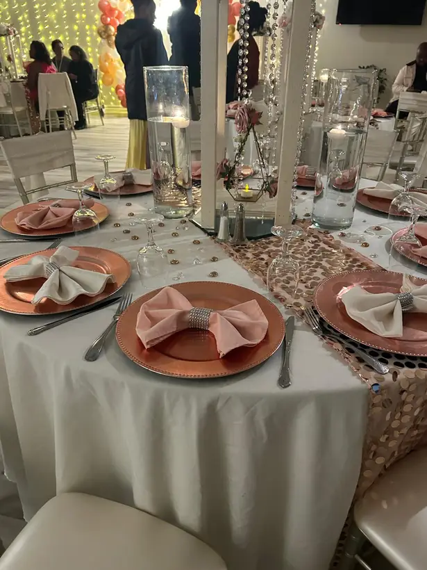 Copper chargers and blush napkins on white linens with a sequin runner