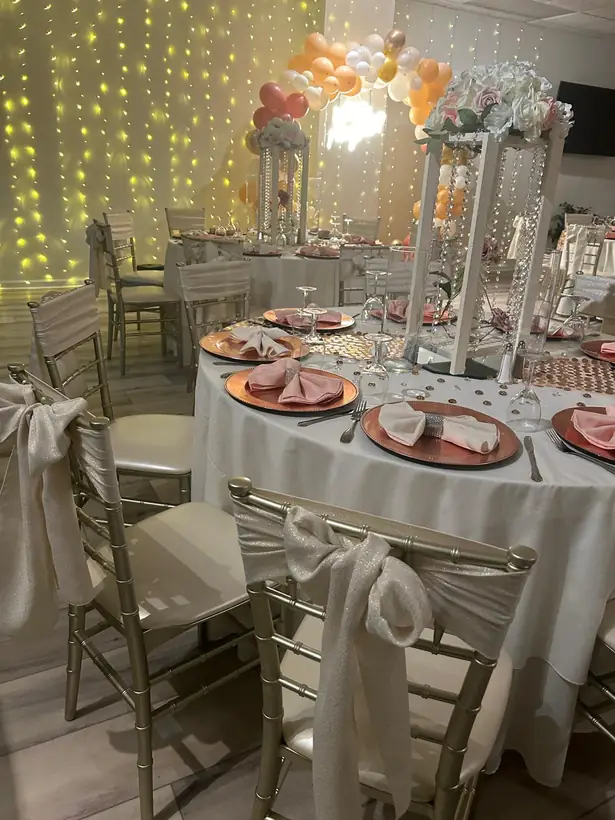 Blush and copper tables beneath a balloon arch and a curtain of lights