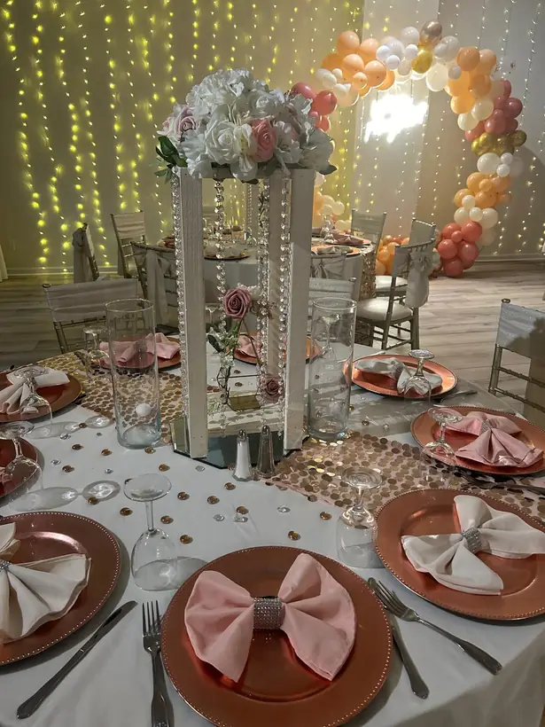Blush bow napkins on copper chargers with a tall floral centerpiece