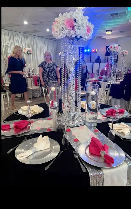 Black linens and pink napkins under a tall crystal and floral centerpiece